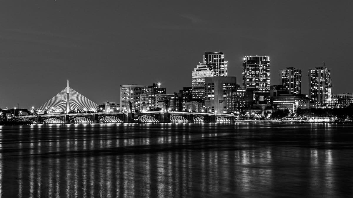 Elegant black and white night view of Boston's illuminated city skyline over Charles River.