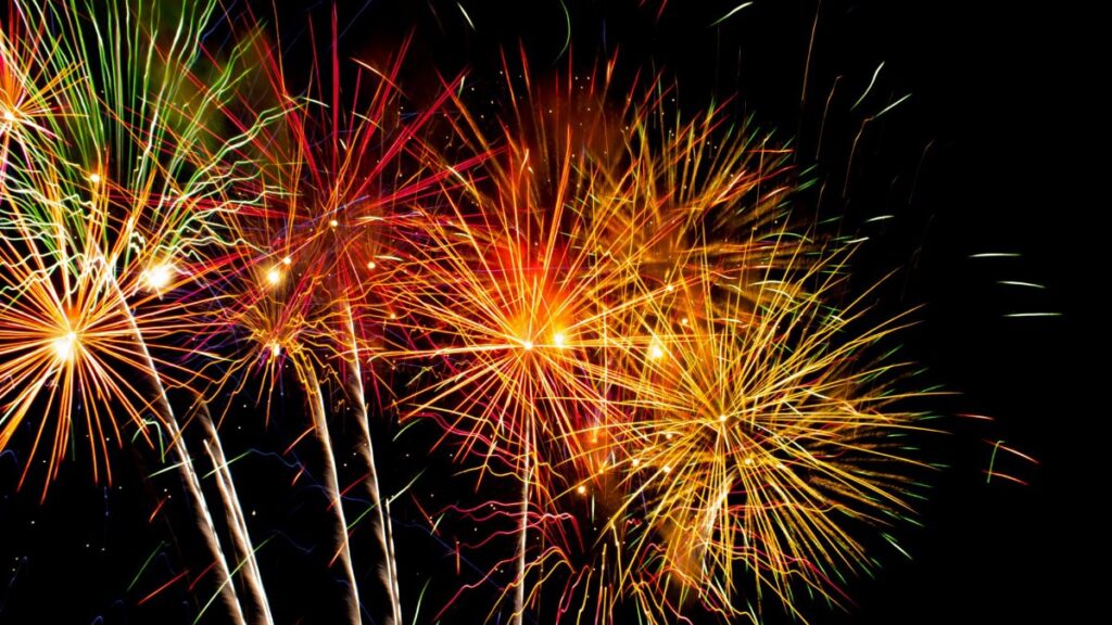 Colorful fireworks explode in the night sky, creating a vivid display of light and color.