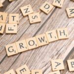 Scrabble tiles spelling 'growth' on a wooden surface symbolize progress and expansion.