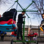 Kids having fun on a colorful carousel in a park setting. Outdoor play and joy.