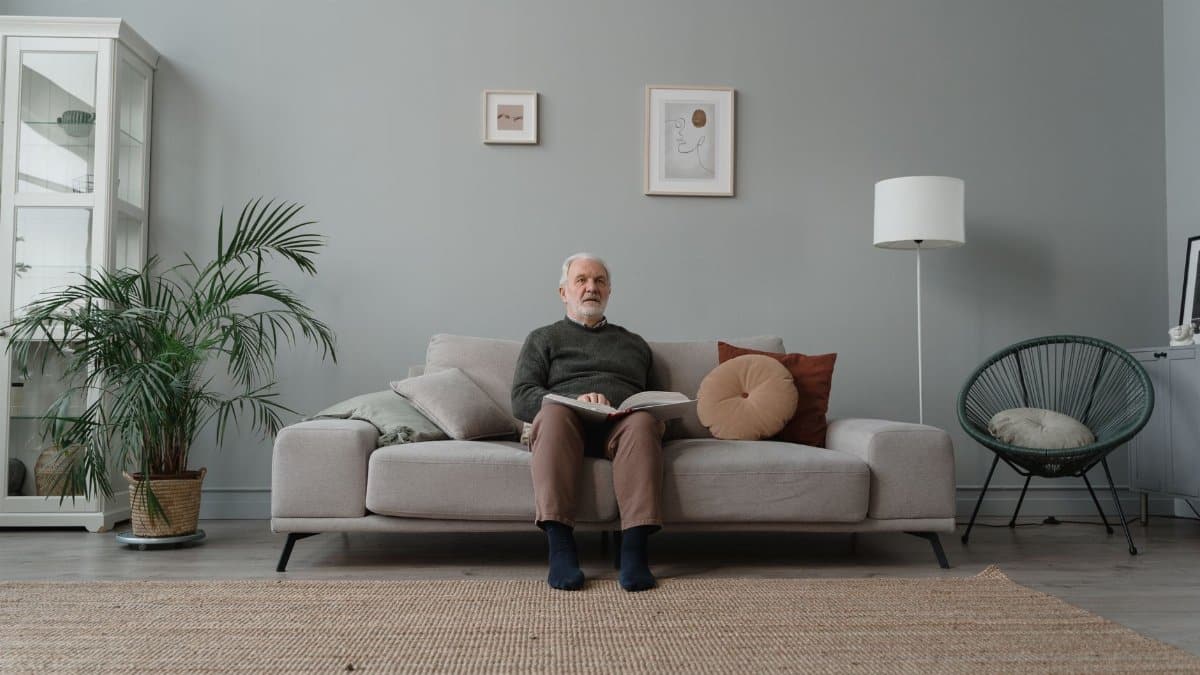 Elderly man enjoying a quiet moment reading on a sofa in a modern living room.