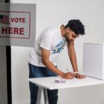 A young man at a polling station voting on election day, symbolizing democracy.