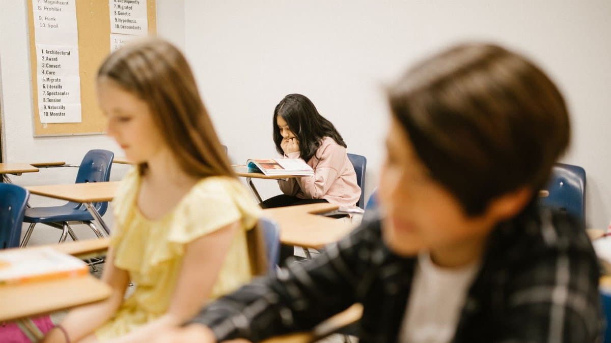 A student sits alone in a school classroom, depicting solitude and contemplation.