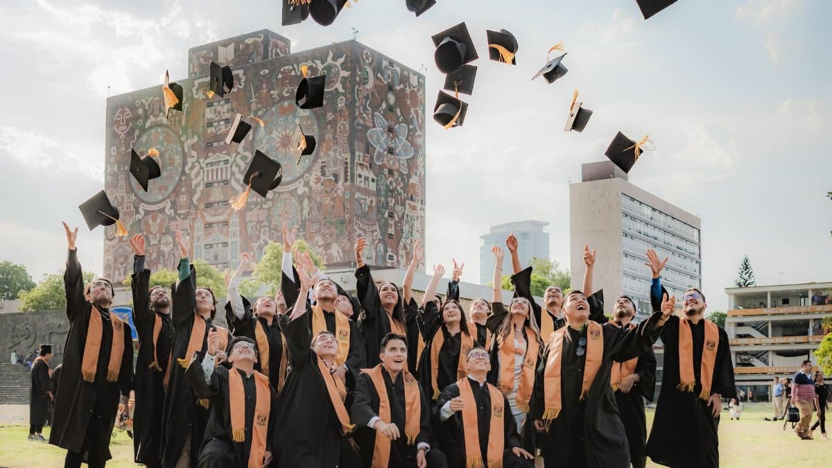 Graduates joyfully toss hats in the air by UNAM Central Library in Mexico City.