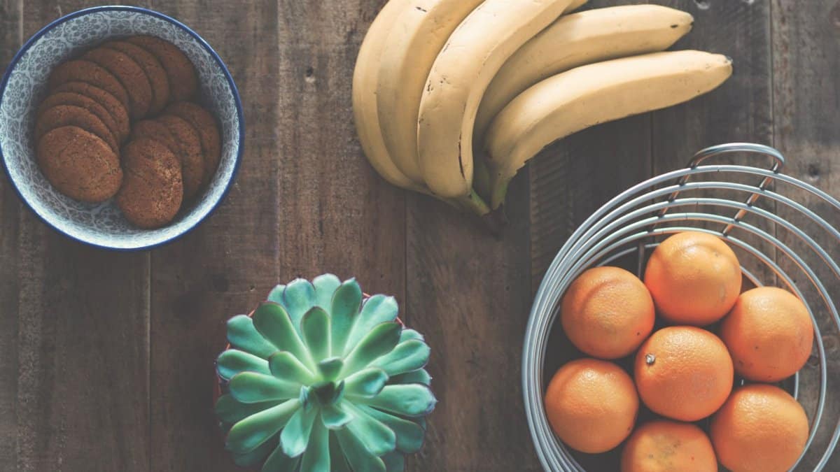 A rustic table setting featuring bananas, oranges, cookies, and a succulent plant.