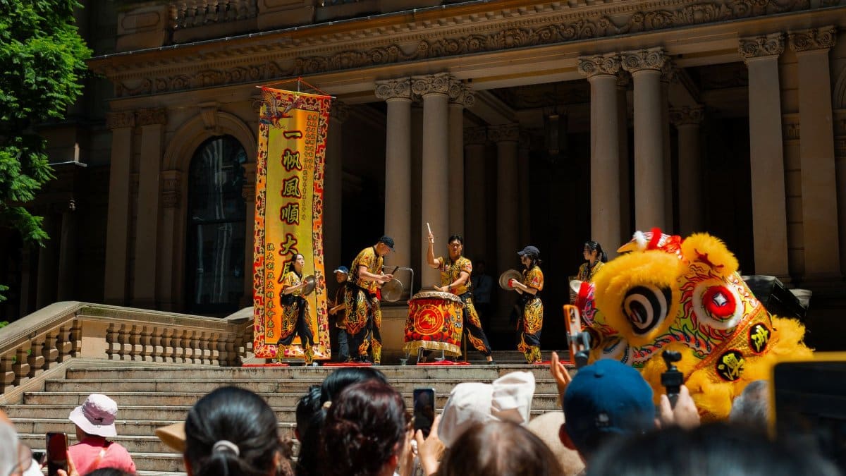 Vibrant Lunar New Year celebration with lion dance in front of historical building, Sydney, Australia.