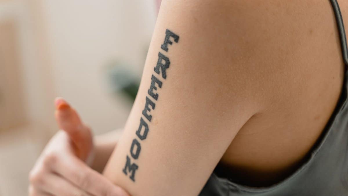 A close-up view of a 'Freedom' tattoo on a woman's arm, symbolizing independence and strength.