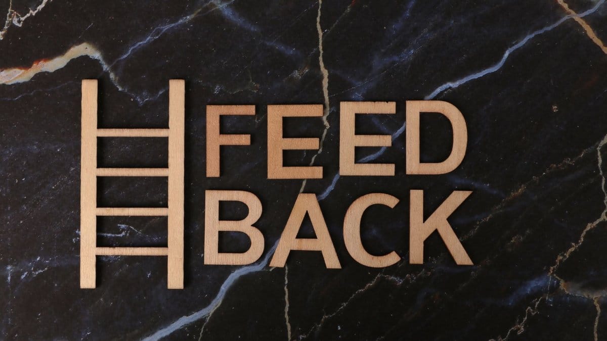 Wooden letters spelling 'Feedback' arranged creatively on a marble surface.