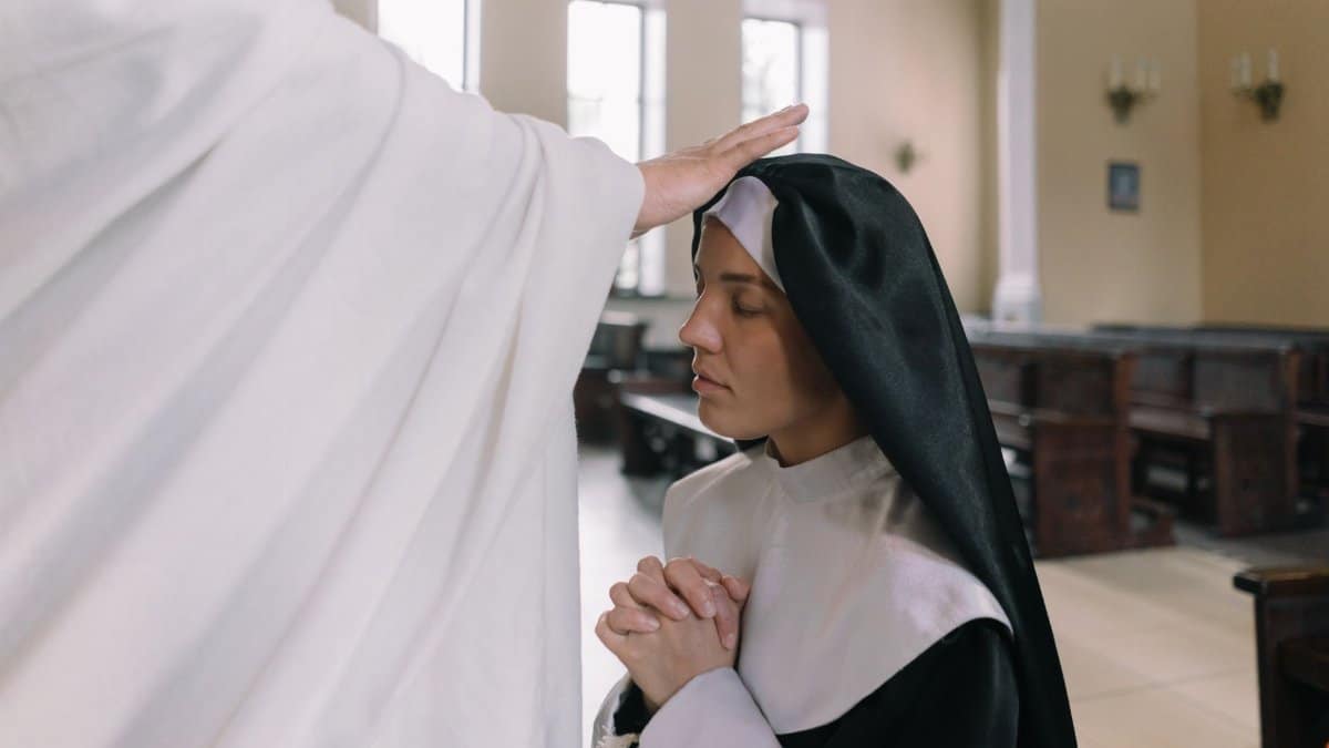 A nun receiving a blessing inside a church, displaying reverence and faith.