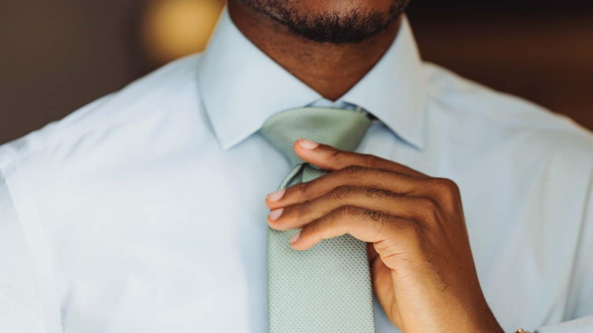 Close-up of a confident professional adjusting his tie, showcasing elegance and style.