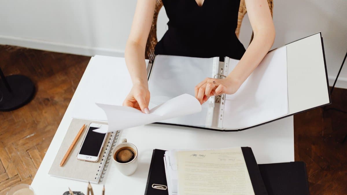 Business professional working with documents at a desk with coffee and smartphone.