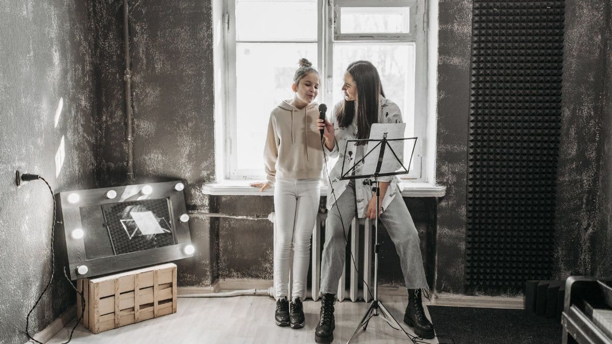 A teenager and teacher singing in a modern studio, enhancing vocal skills.