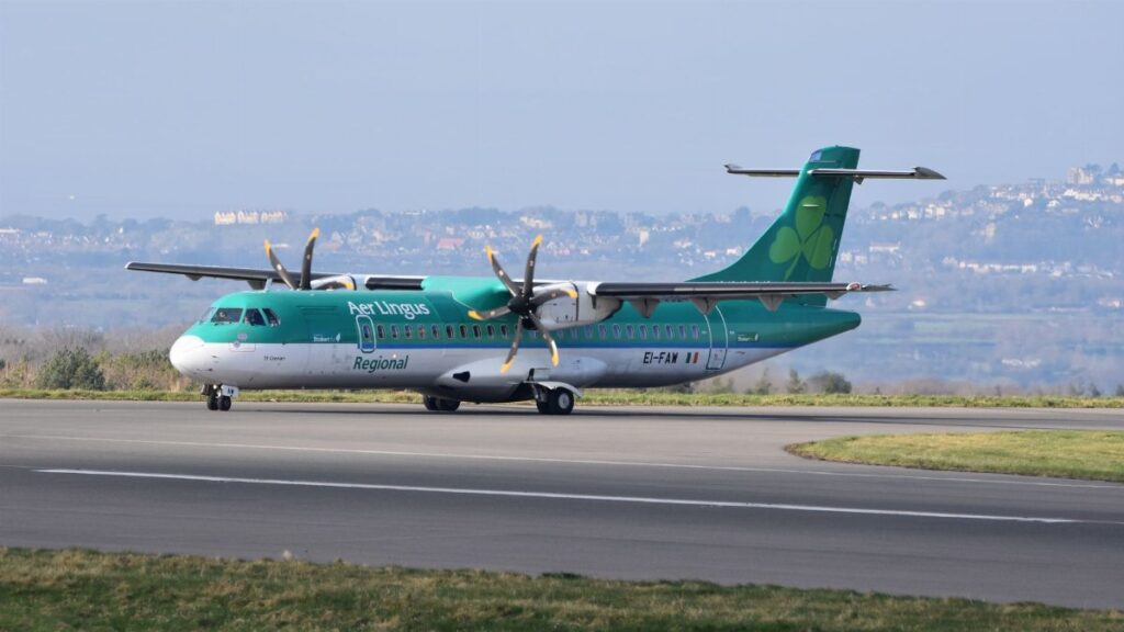 Aer Lingus Regional passenger plane taxiing on an airport runway with scenic background.