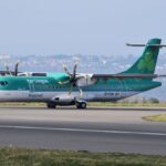 Aer Lingus Regional passenger plane taxiing on an airport runway with scenic background.