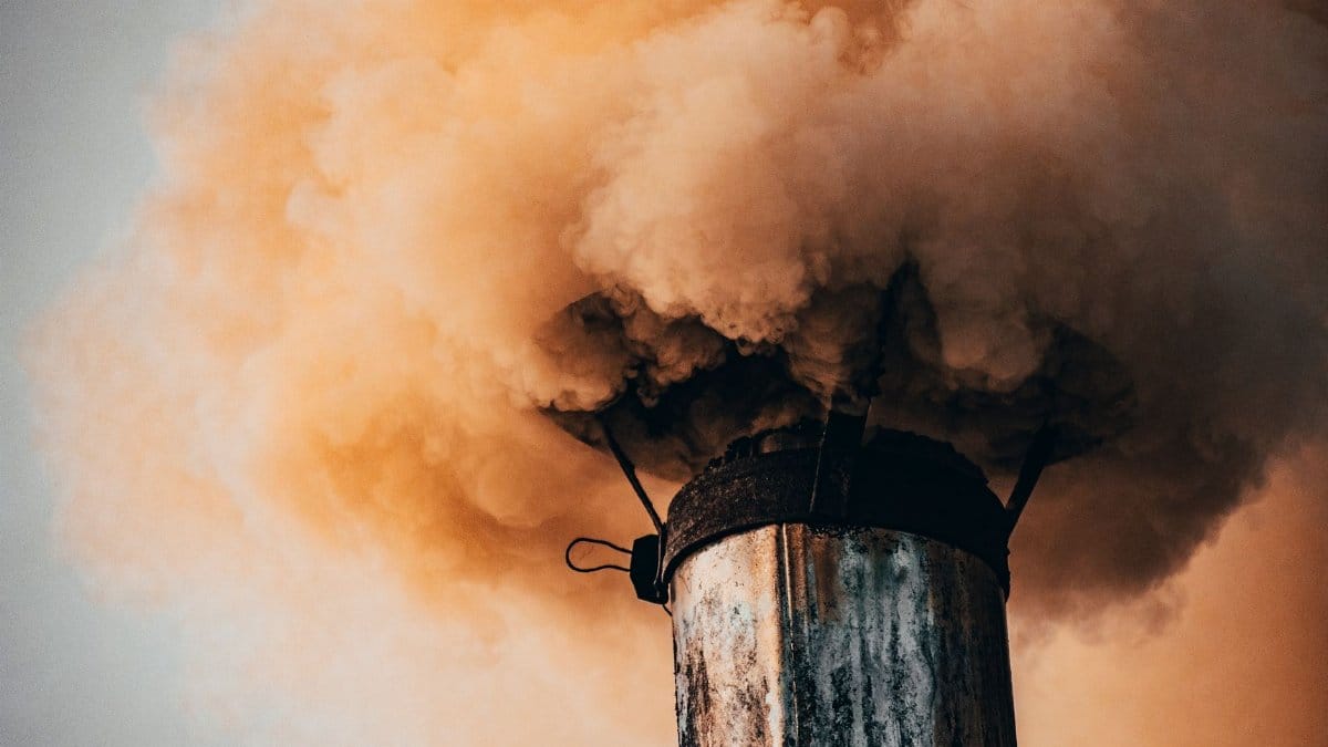 A close-up of a factory smokestack releasing thick smoke into the air, illustrating industrial pollution.