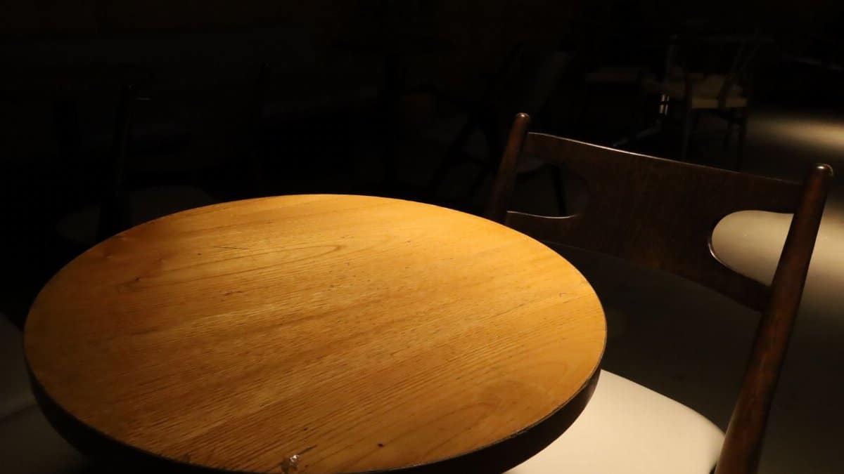A round wooden table and chair in a dimly lit, intimate indoor cafe setting.
