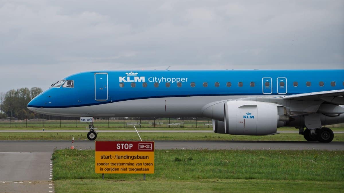 Side view of KLM Cityhopper aircraft on a runway with a stop sign, overcast day.