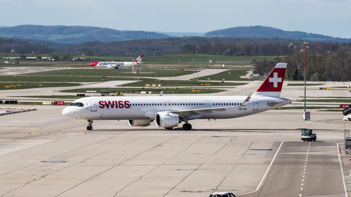 A Swiss Airbus A321 aircraft on the Zurich airport apron with scenic landscape.