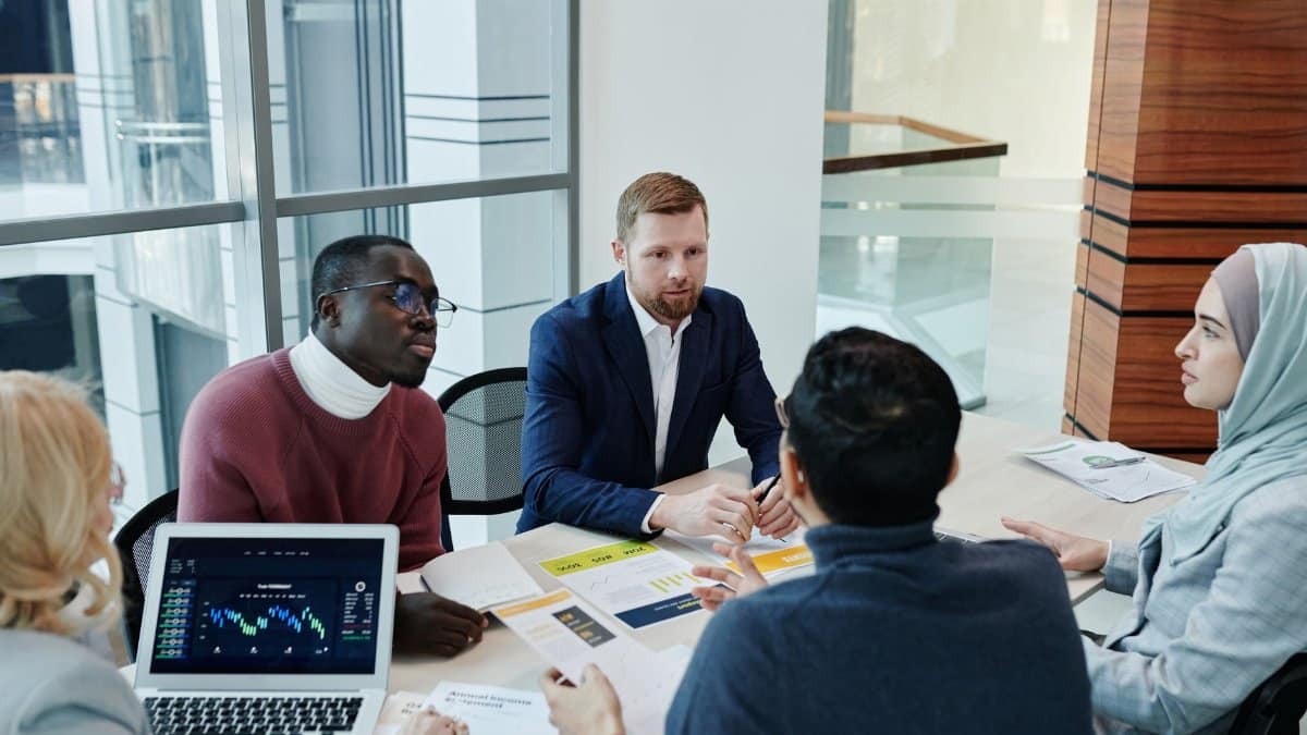 A diverse group of professionals engaged in an office meeting, discussing business strategies.