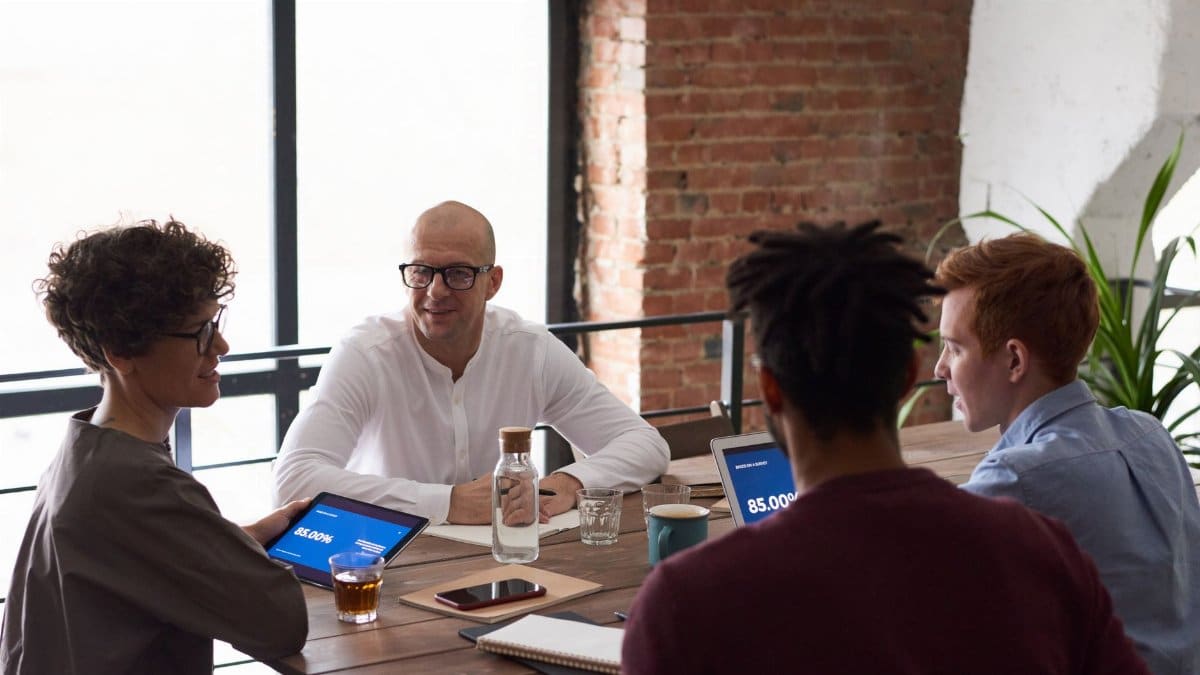 Diverse team collaborating in a modern office setting with laptops and notes on the table.