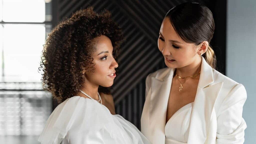 Elegant women smiling and connecting in chic white attire, highlighting friendship.