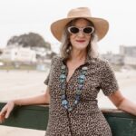 Confident senior woman in stylish attire enjoys a relaxed day at the beach.