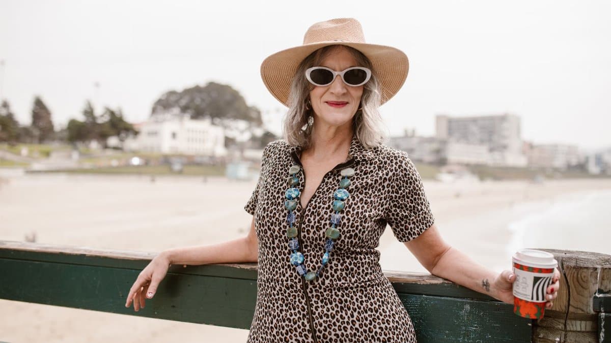 Confident senior woman in stylish attire enjoys a relaxed day at the beach.