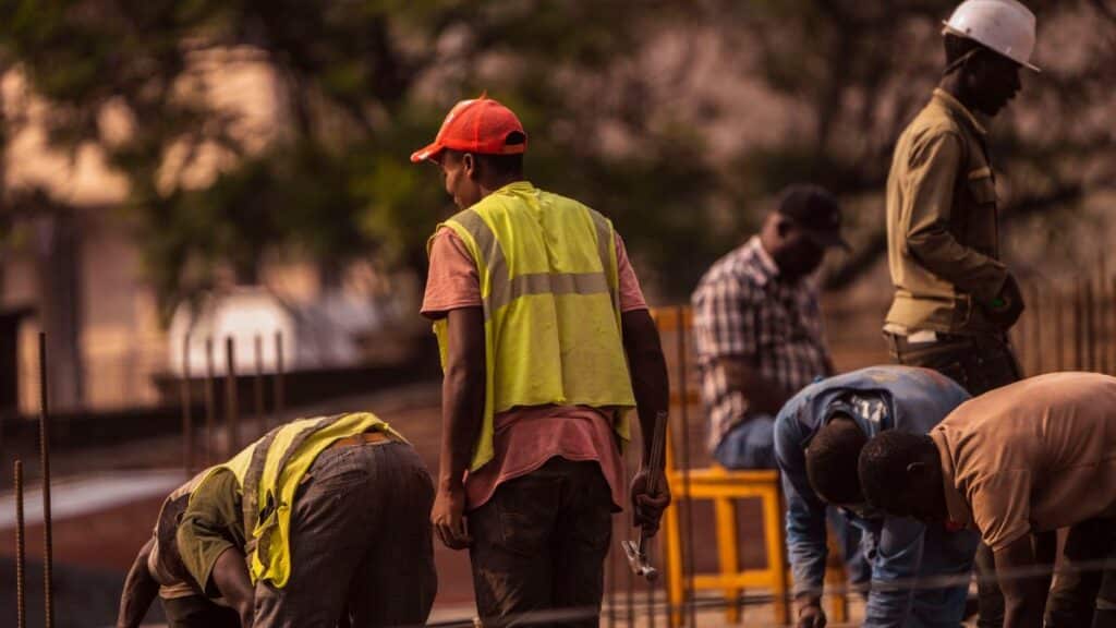Group of male construction workers on site wearing safety gear during daytime.
