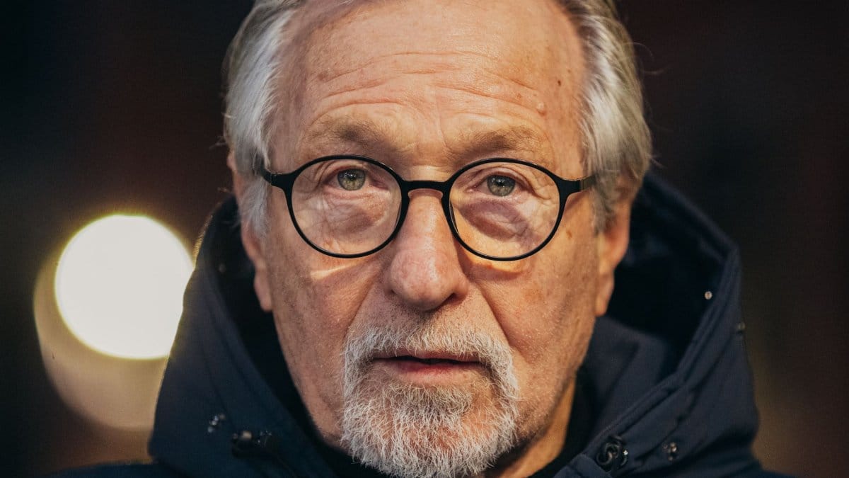 Portrait of a senior man with glasses and beard in a hooded jacket.
