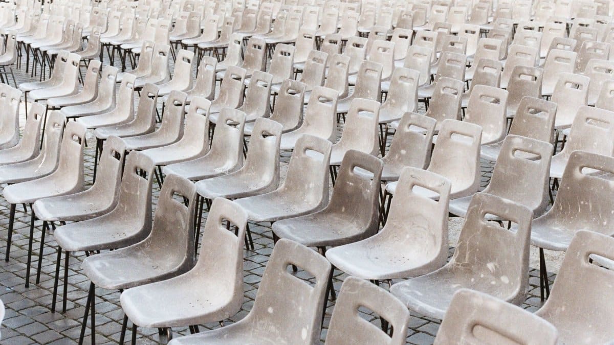 A view of numerous vacant chairs arranged in rows on a cobblestone floor, outdoors in Vatican City.