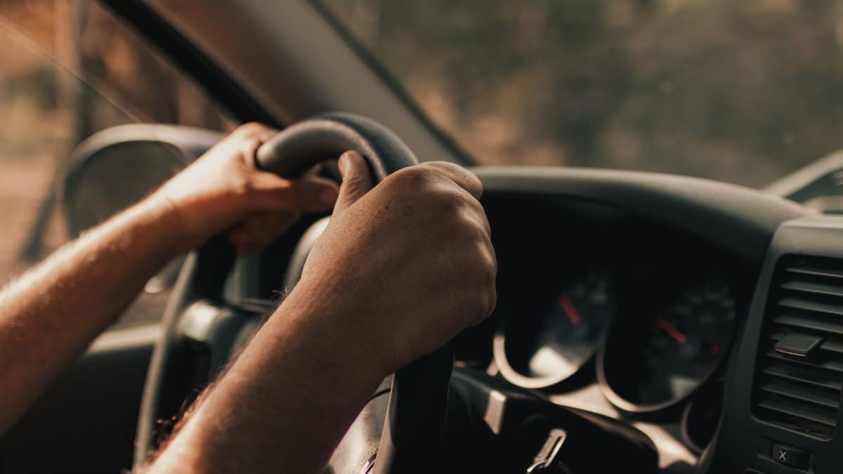 Driver's hands on a steering wheel inside a vehicle, focusing on the act of driving.