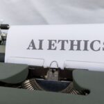 Close-up of vintage typewriter with 'AI ETHICS' typed on paper, emphasizing technology and responsibility.