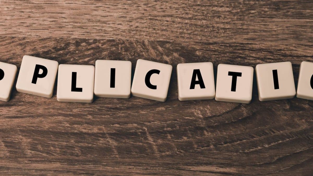 Scrabble letter tiles spelling 'application' on a wooden surface.