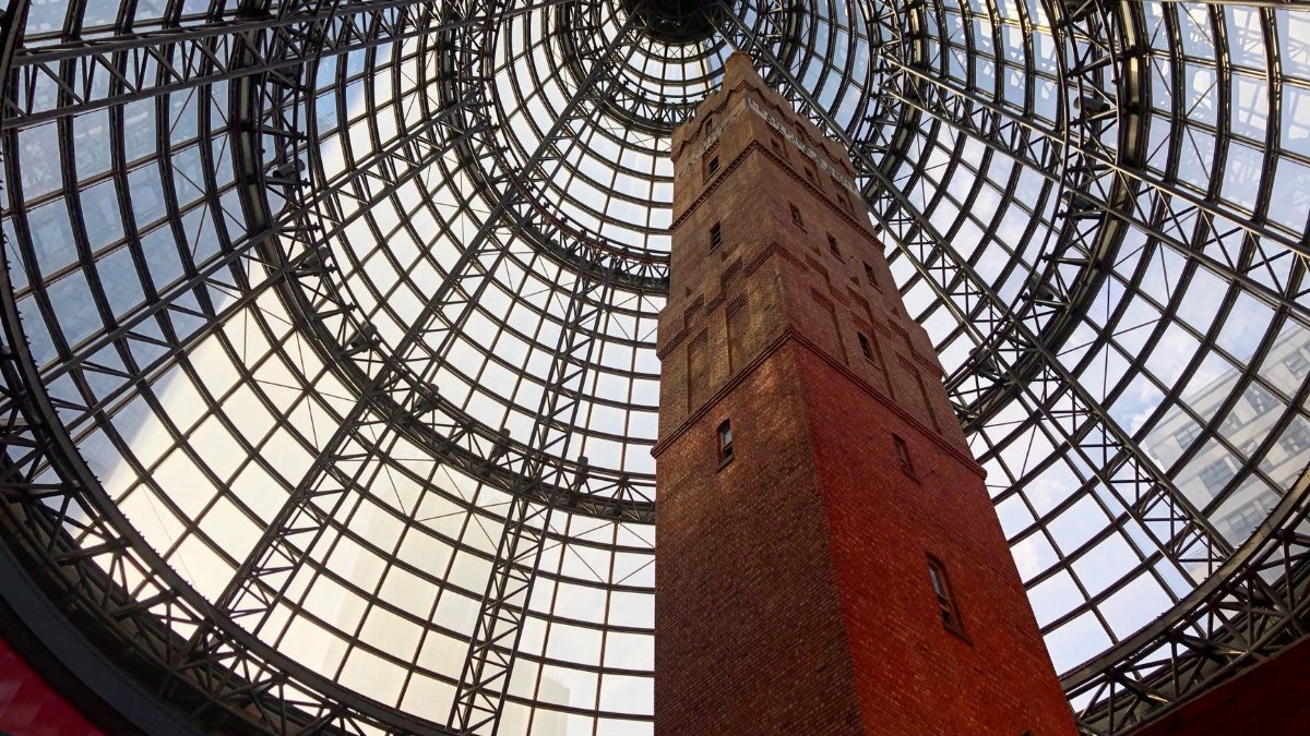 Dramatic low-angle view of Coops Shot Tower under glass dome in Melbourne mall.
