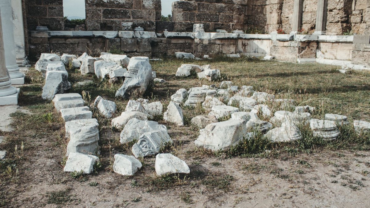 Explore ancient ruins with scattered stone fragments and architectural remnants under a clear sky.