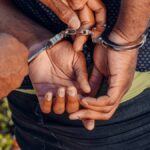 Close-up of a police officer handcuffing a man outdoors. Law enforcement in action.