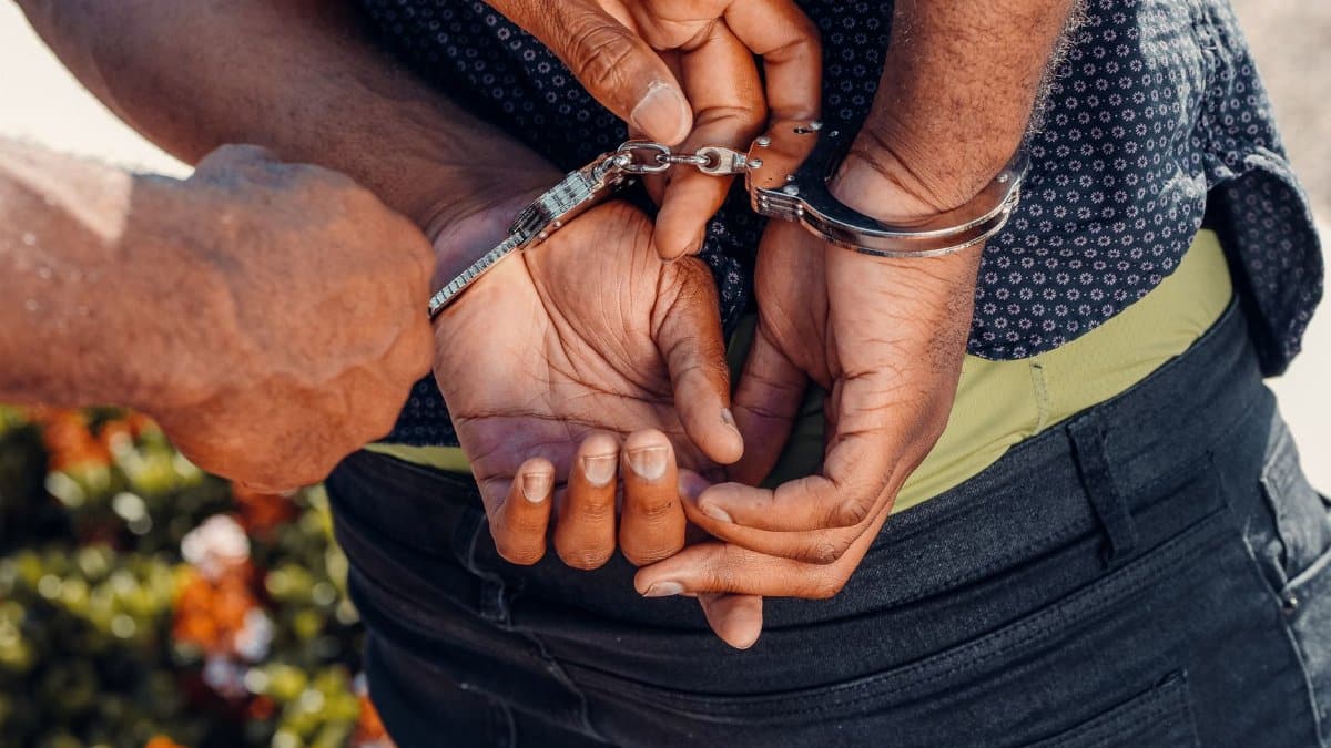 Close-up of a police officer handcuffing a man outdoors. Law enforcement in action.