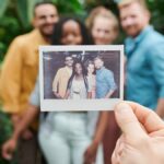 A group of friends enjoying a moment with an instant camera photo surrounded by lush greenery.