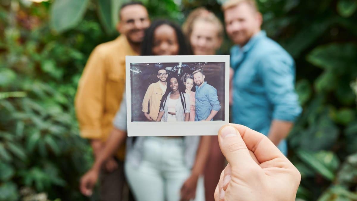 A group of friends enjoying a moment with an instant camera photo surrounded by lush greenery.