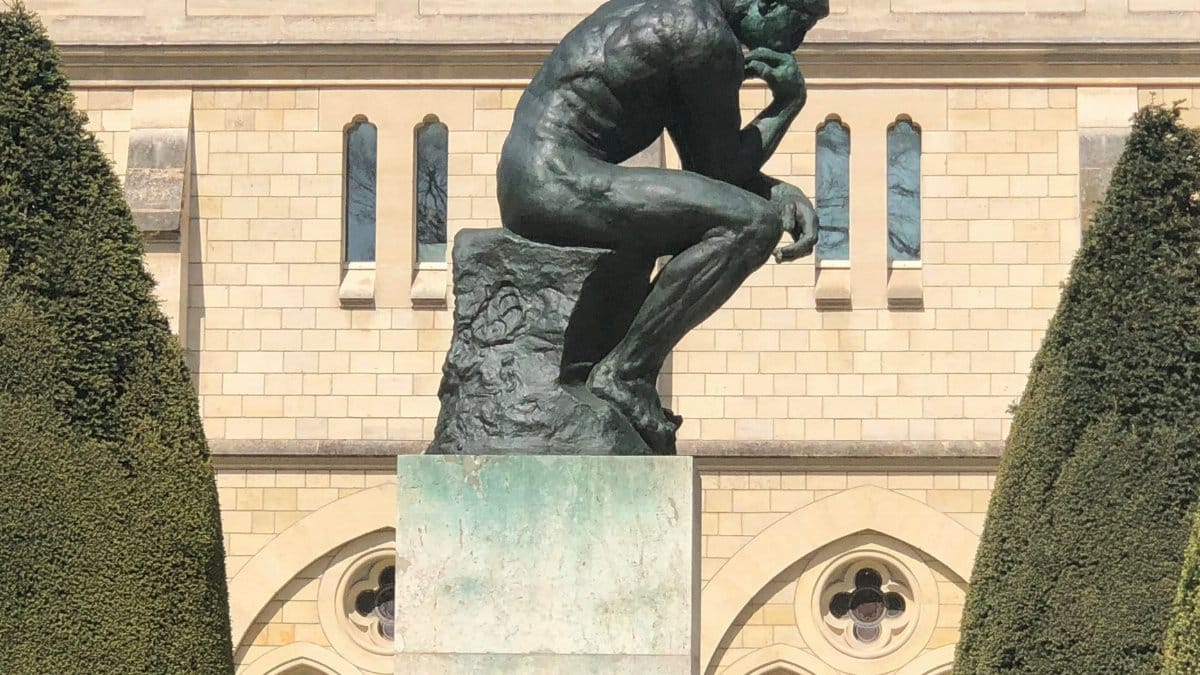 The iconic Thinker statue in Paris in front of a historic building.