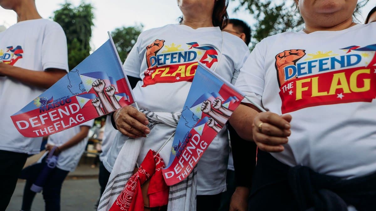 Group gathering outdoors with 'Defend the Flag' banners and shirts promoting national pride.