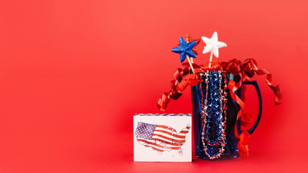 A festive display of red, white, and blue patriotic decor against a vibrant red background, perfect for July 4th celebrations.