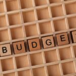 Wooden letter tiles spelling 'budget' on a wooden grid background, symbolizing finance and planning.