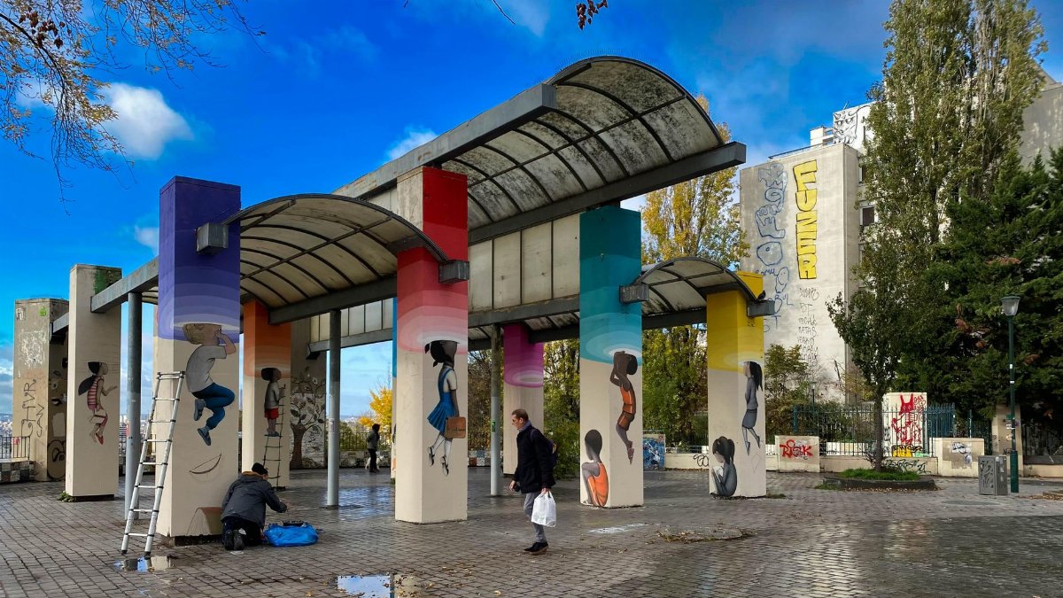 Urban art featuring colorful graffiti mural on a modern architectural structure in a public space.