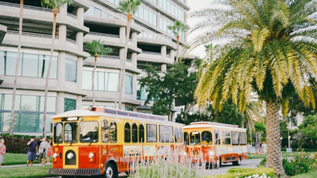 Vibrant Tampa street with iconic trolleys, palm trees, and modern architecture.