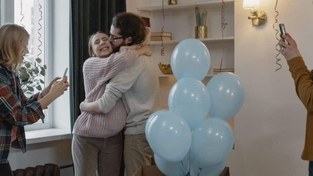 Couple celebrating new parenthood with friends at home during a gender reveal party.