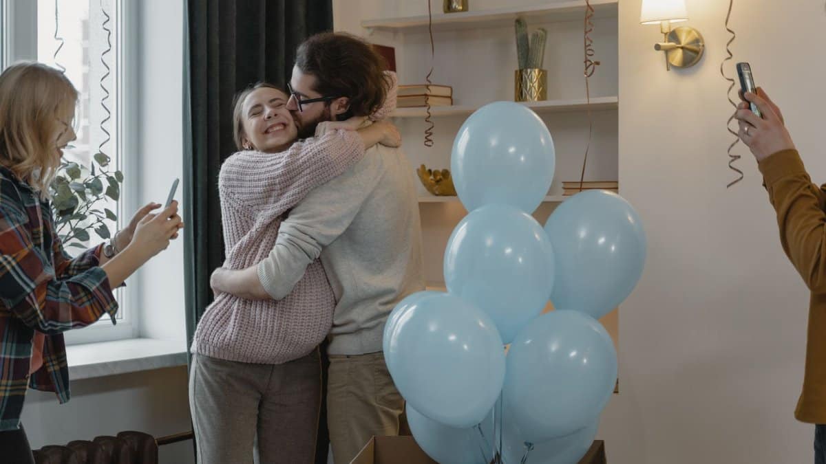 Couple celebrating new parenthood with friends at home during a gender reveal party.