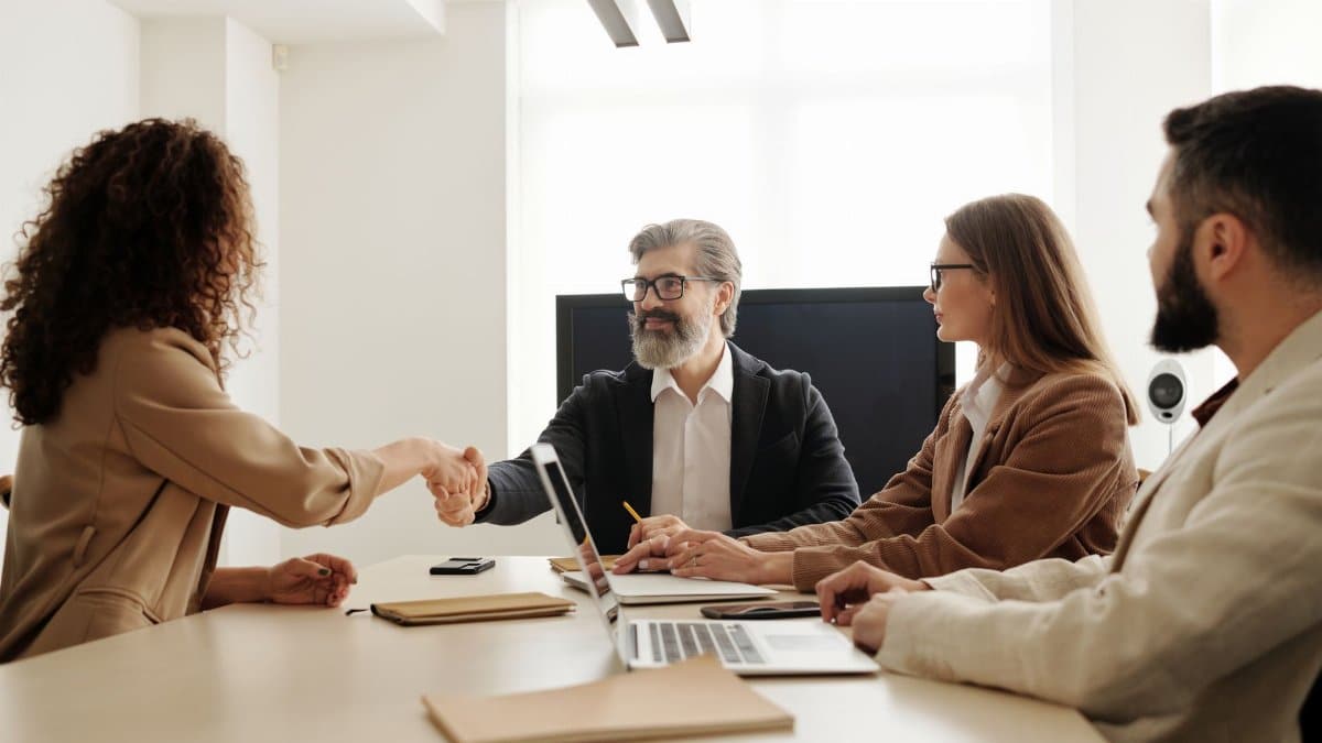 Colleagues in an office celebrating a successful negotiation with a handshake.
