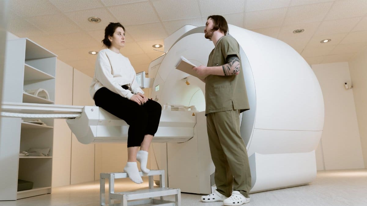 Medical professional consulting a patient near an MRI machine in a hospital setting.