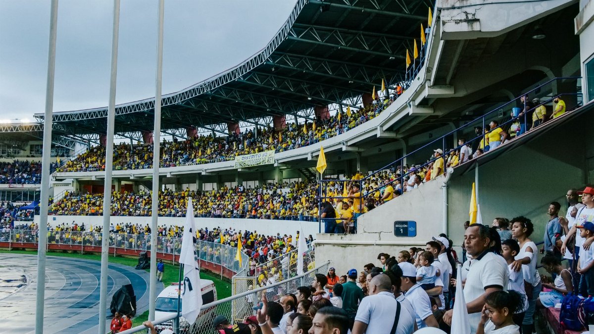 Energetic fans fill a stadium, creating an exciting sports atmosphere on an overcast day.
